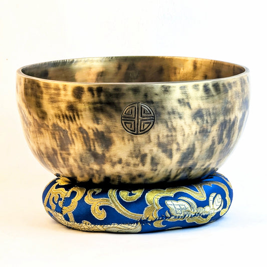 Tibetan singing bowl with decorative base on a white background