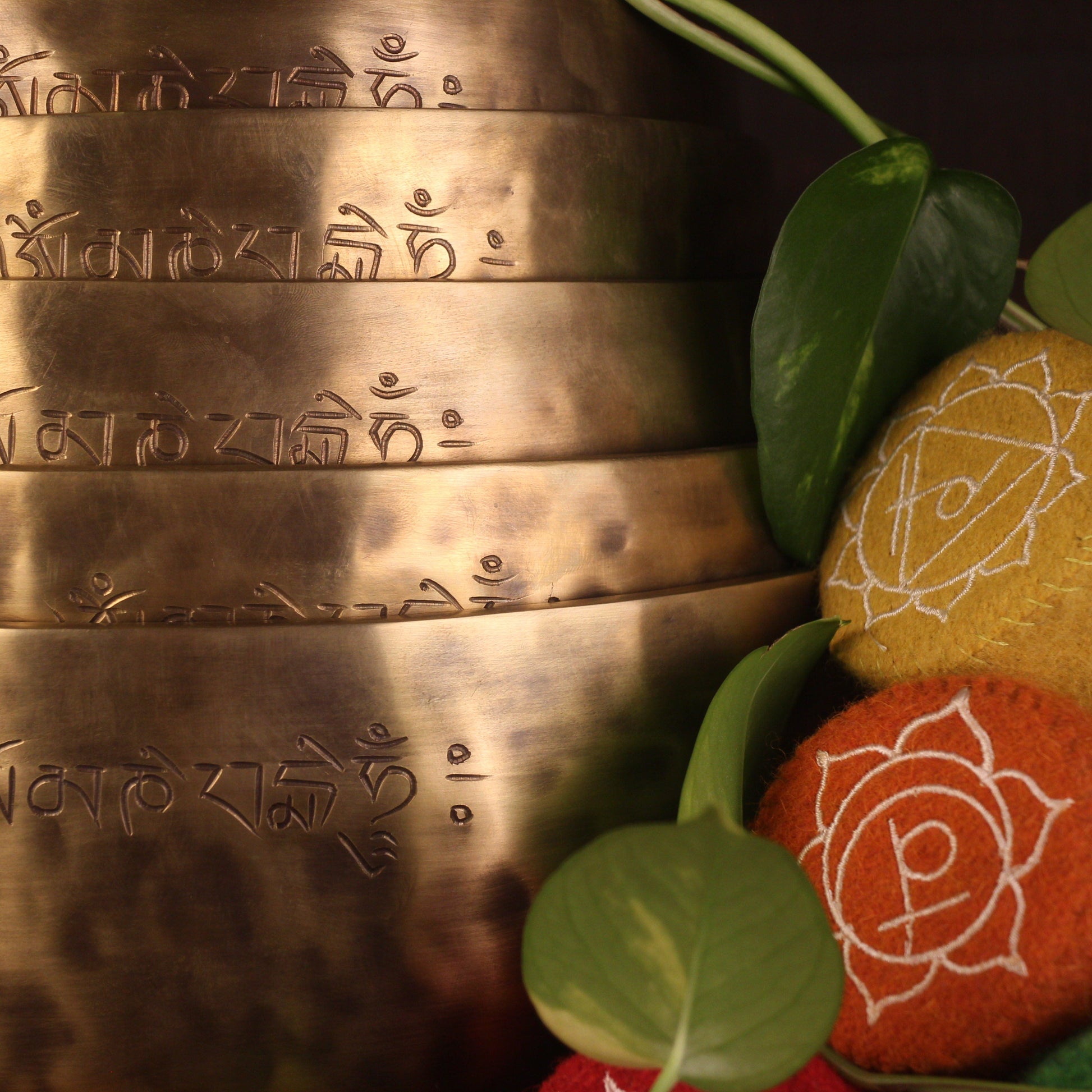 Bronze bell with engraved text and colorful fabric with floral patterns on a dark background