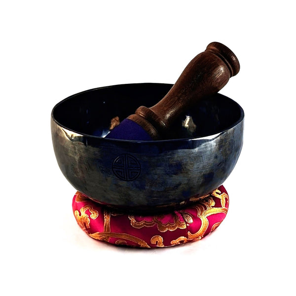 Tibetan singing bowl with a wooden striker on a white background