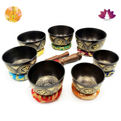 Set of black singing bowls with gold Om symbols on colorful stands, accompanied by wooden mallets.