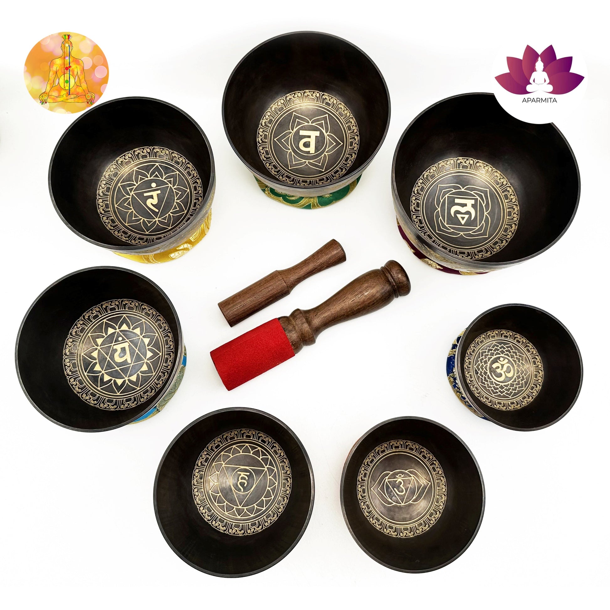 Set of black singing bowls with decorative symbols and wooden striking tools on a white background.