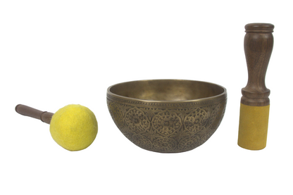 Decorative bronze singing bowl with a mallet and beater on a white background