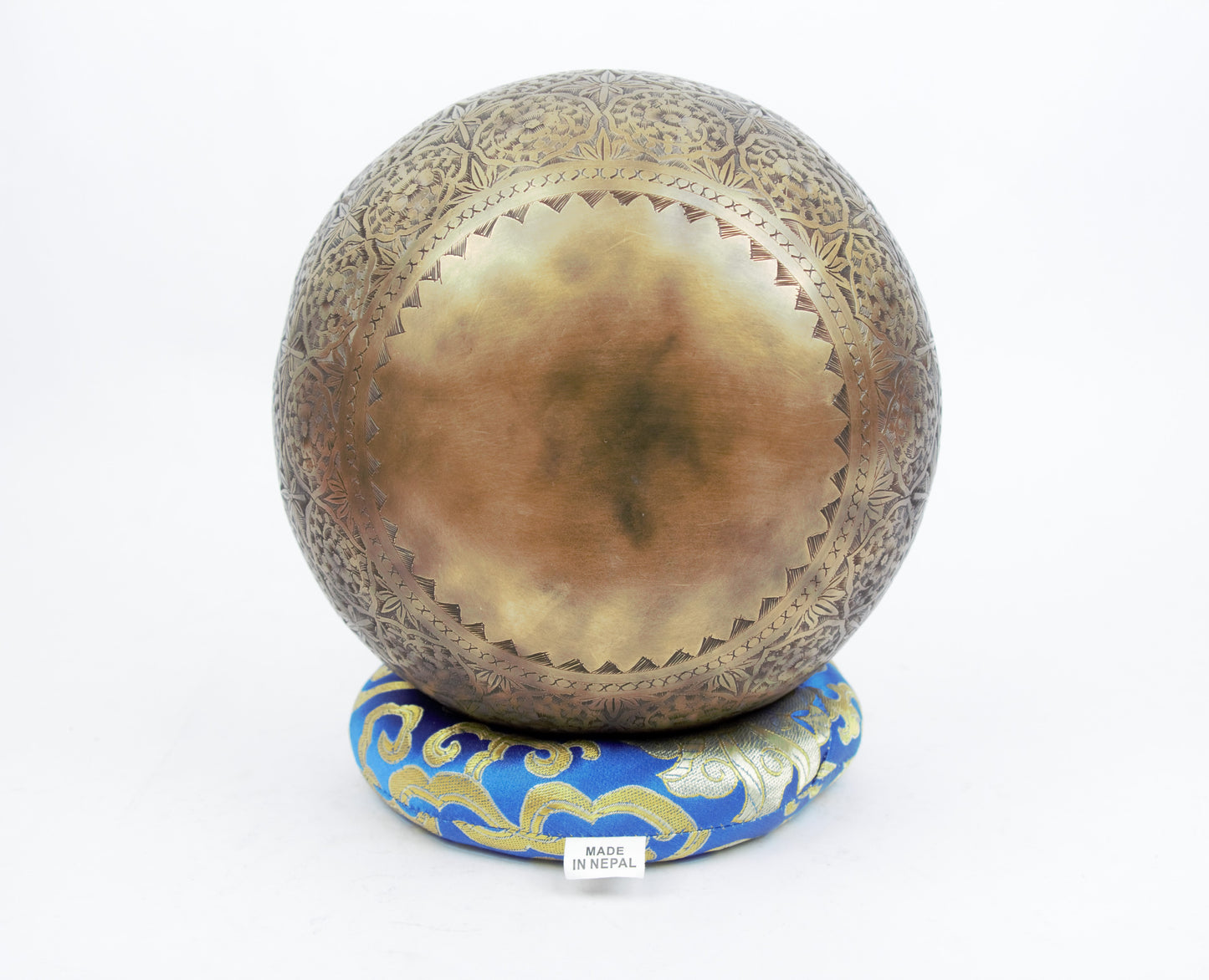 Decorative brass sphere with intricate patterns on a white background