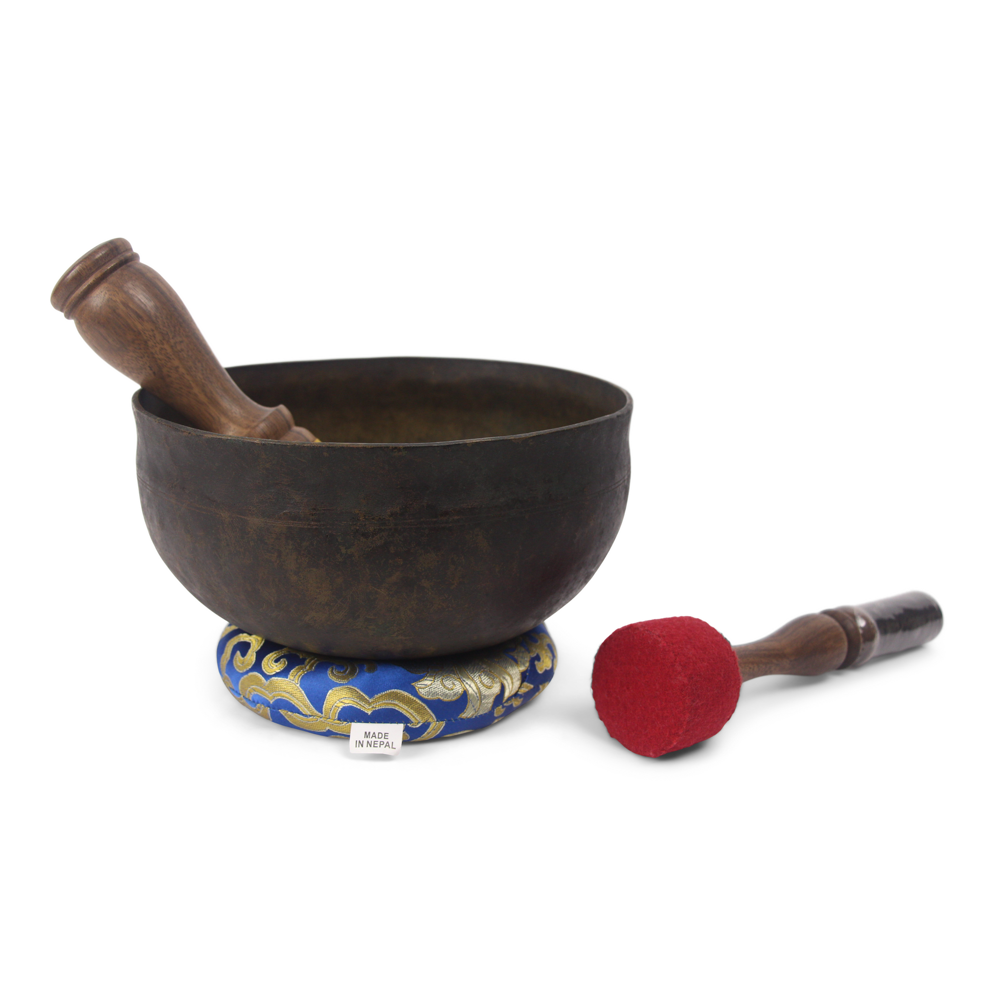 Tibetan singing bowl with wooden mallet and decorative mat on a white background
