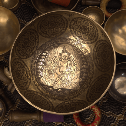 Decorative metal bowl with intricate designs and a central figure, surrounded by other similar items.
