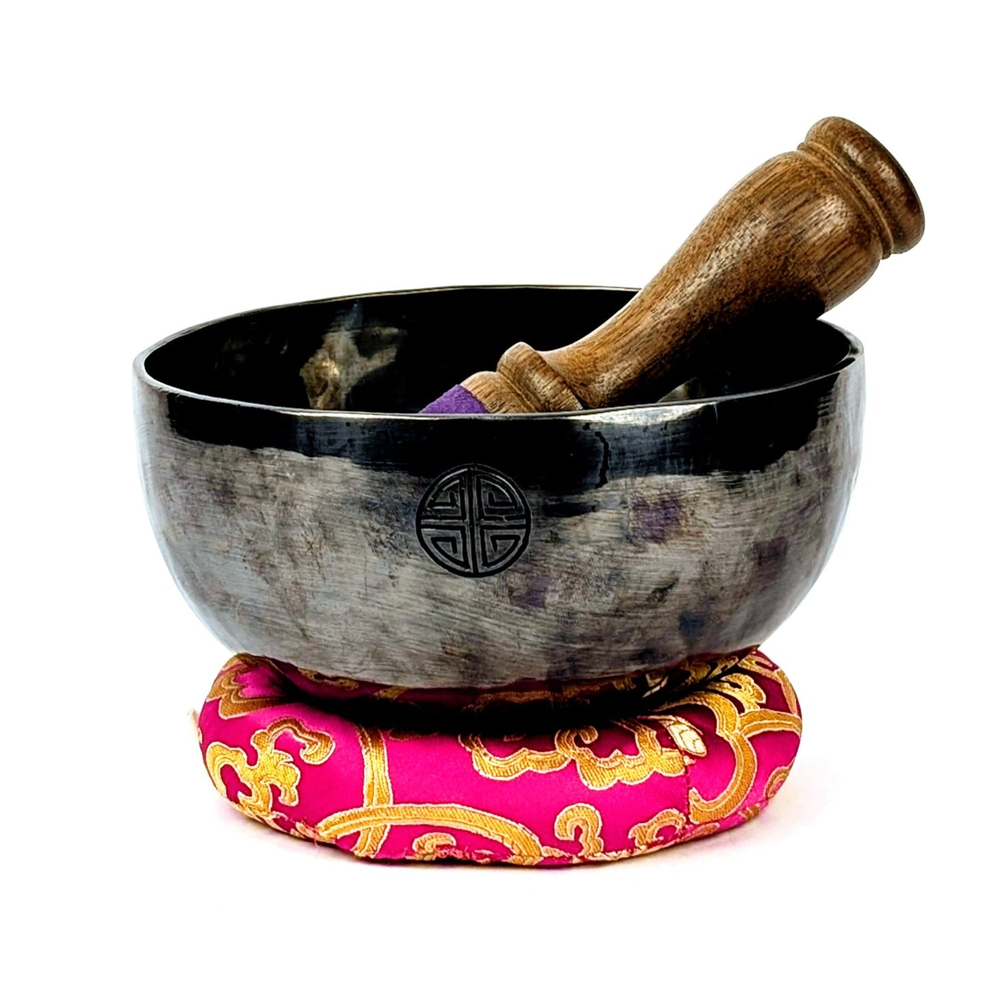 Tibetan full moon singing bowl with wooden mallet on a pink and gold cushion against a white background