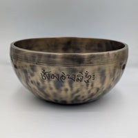 Bronze singing bowl with engraved text on a white background