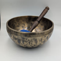 Tibetan singing bowl with a wooden striker on a white background