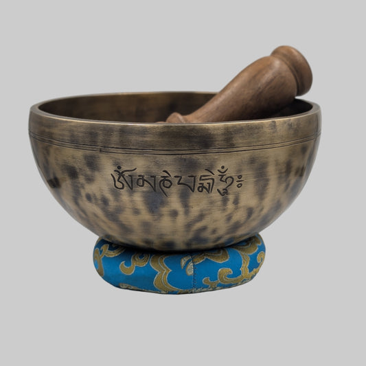 Tibetan singing bowl with a wooden striker on a white background
