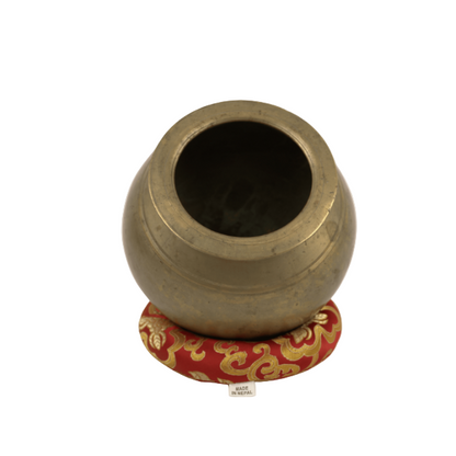 Bronze pot on a red and gold decorative stand against a white background