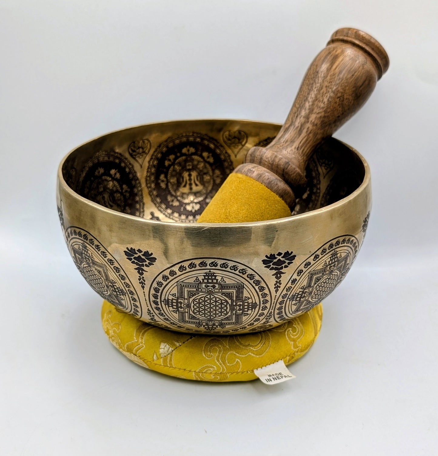 Brass singing bowl with wooden striker on a white background