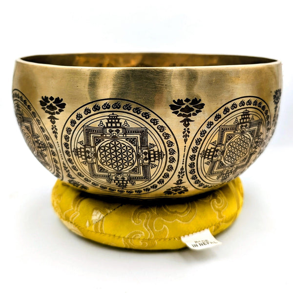 Brass singing bowl with intricate designs on a white background