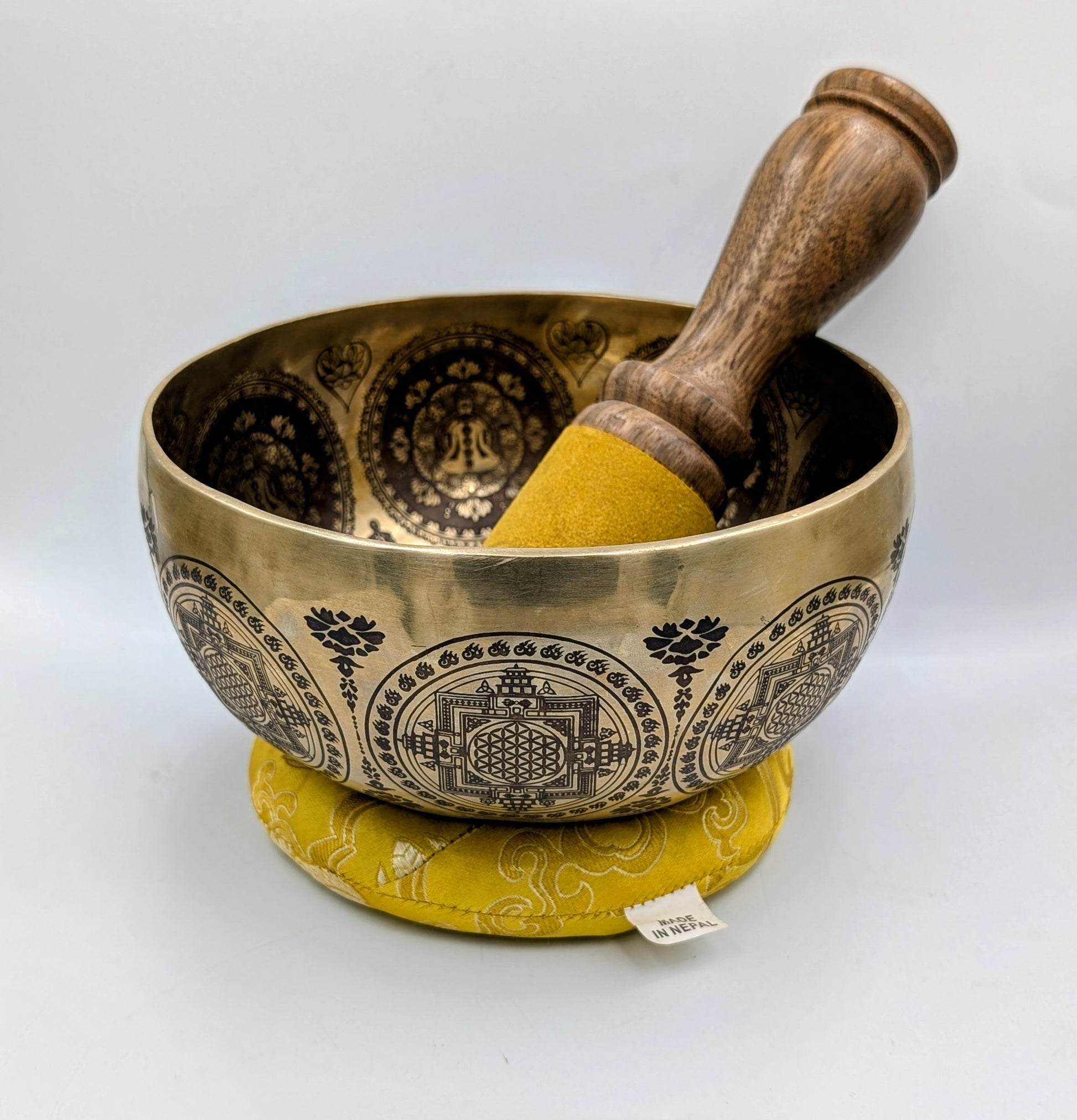 Brass singing bowl with wooden striker on a white background