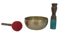 Brass singing bowl with a red mallet and wooden striker on a white background