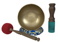 Brass singing bowl with wooden mallet and red cushion on a white background