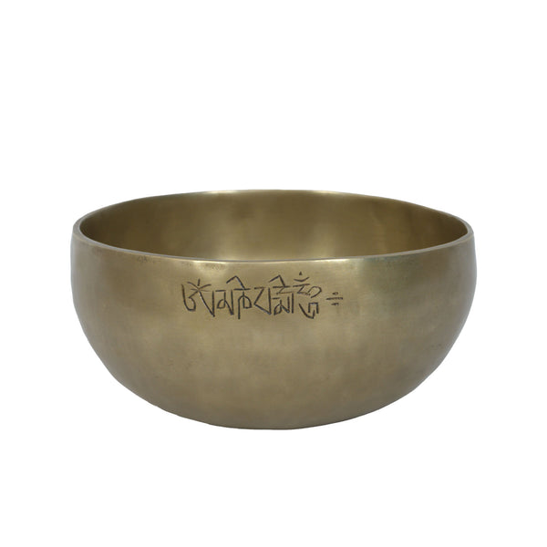 Brass singing bowl with engraved text on a white background
