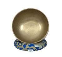 Brass singing bowl on a blue and gold decorative stand with 'Made in Nepal' label.
