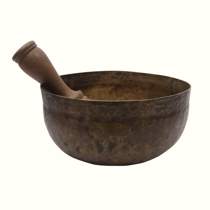 Bronze singing bowl with wooden striker on a white background