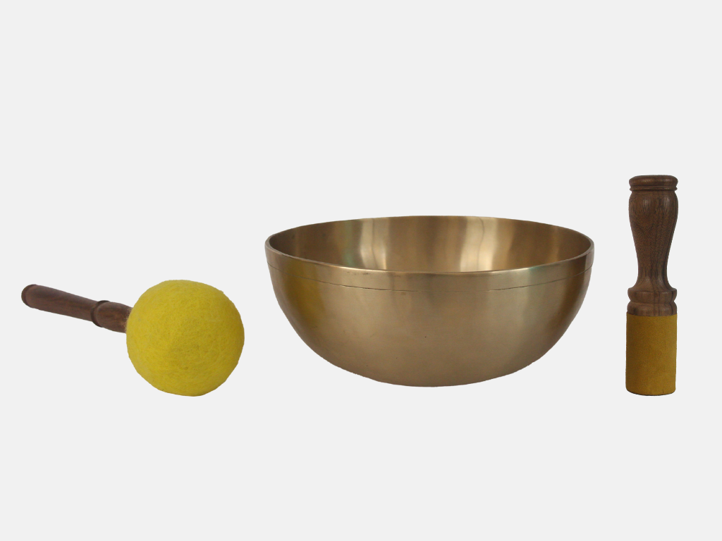 Brass singing bowl with two wooden mallets on a white background
