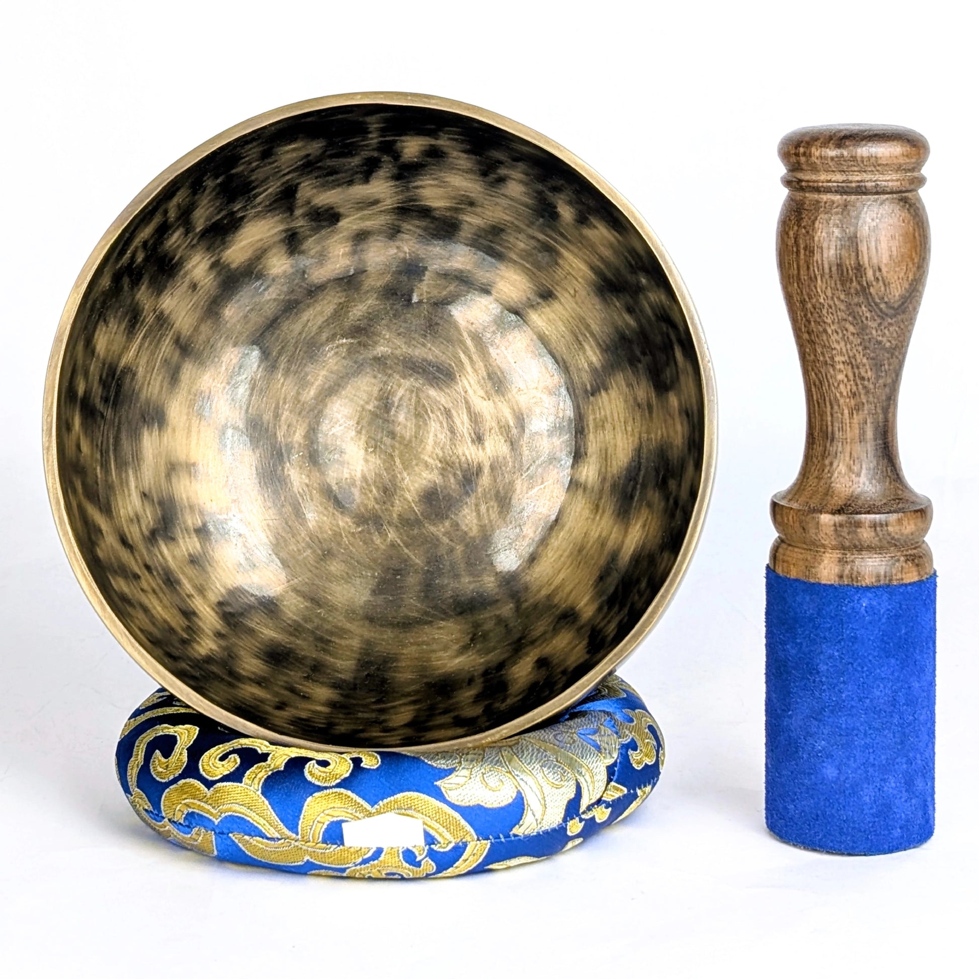 Tibetan singing bowl with decorative base and wooden striker on a white background