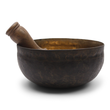 Bronze singing bowl with wooden handle on a white background